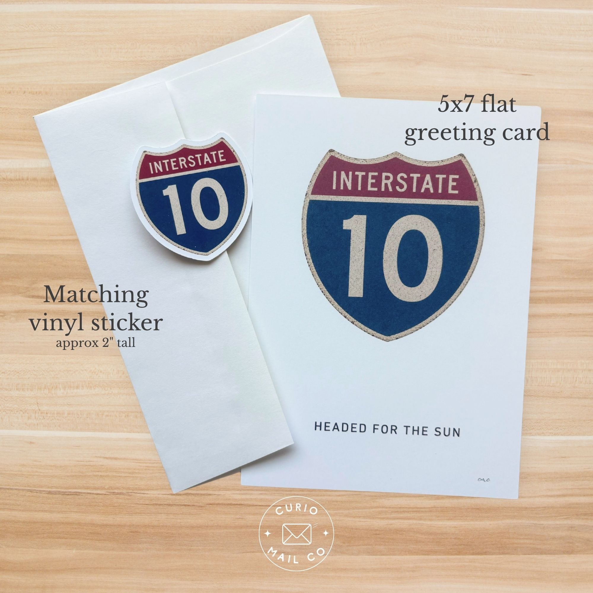 5x7 flat greeting card with Interstate 10 design and matching vinyl sticker on a wooden surface.