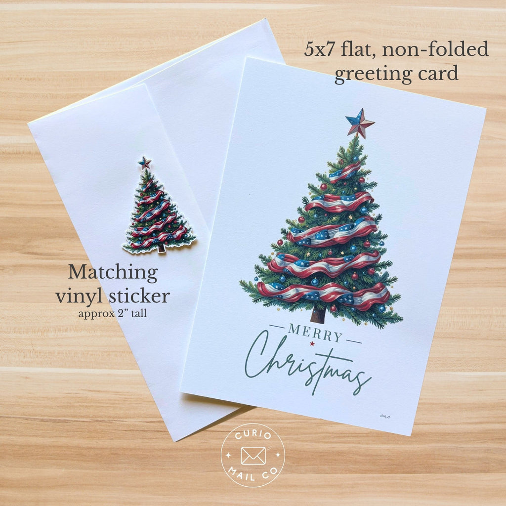 A white greeting card with a colorful Christmas tree illustration and the words 'Merry Christmas' is shown on a light wood background, alongside a matching vinyl sticker of the tree and text noting a 5x7 flat non-folded greeting card and matching vinyl sticker.