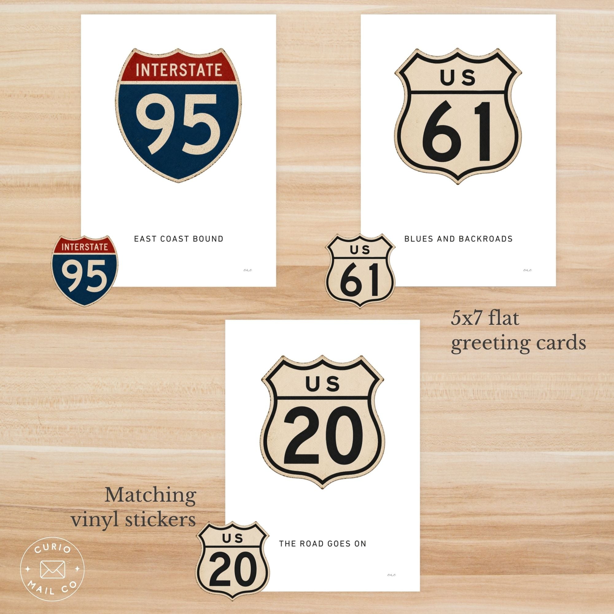 Set of greeting cards and vinyl stickers with US route symbols on a wooden surface.