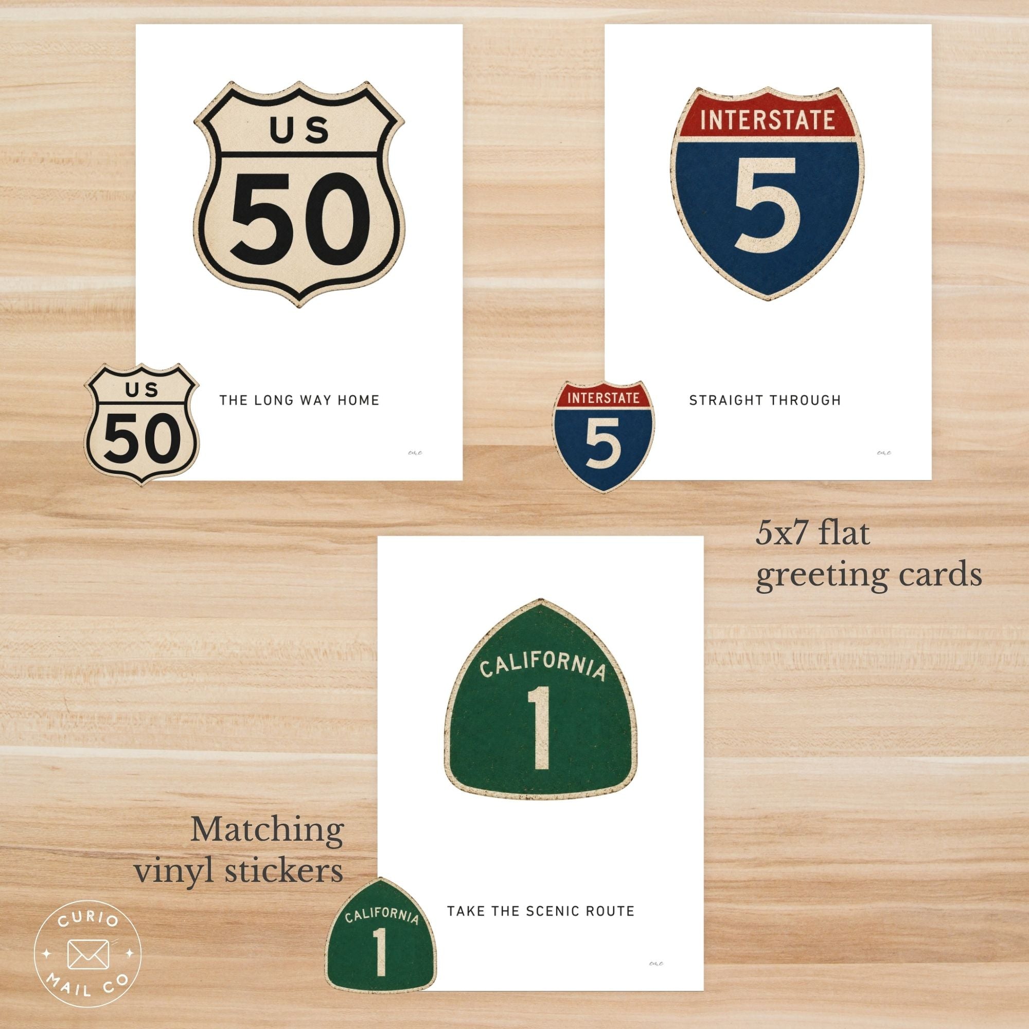 Set of 5x7 flat greeting cards and matching vinyl stickers with road sign designs on a wooden surface.