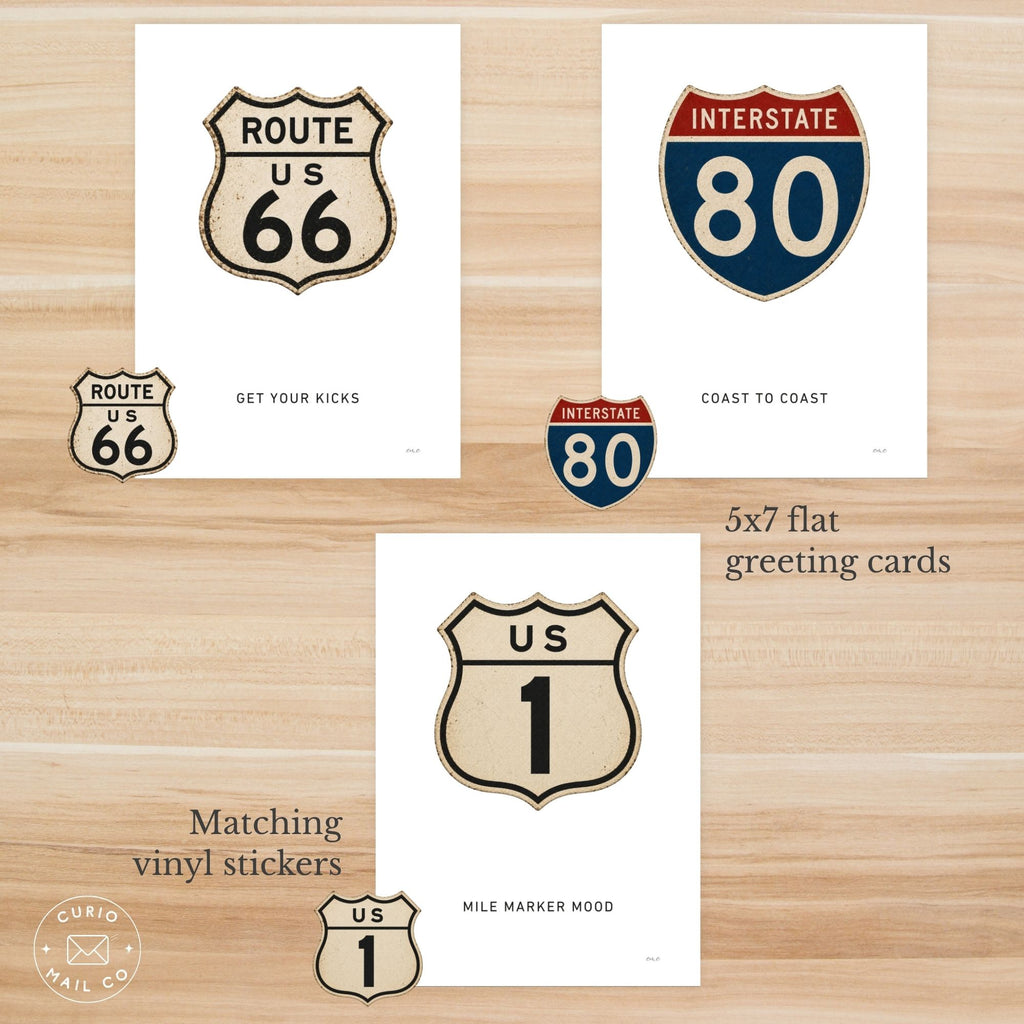 Set of Route 66, Interstate 80, and US 1 themed greeting cards and vinyl stickers on a wooden surface.