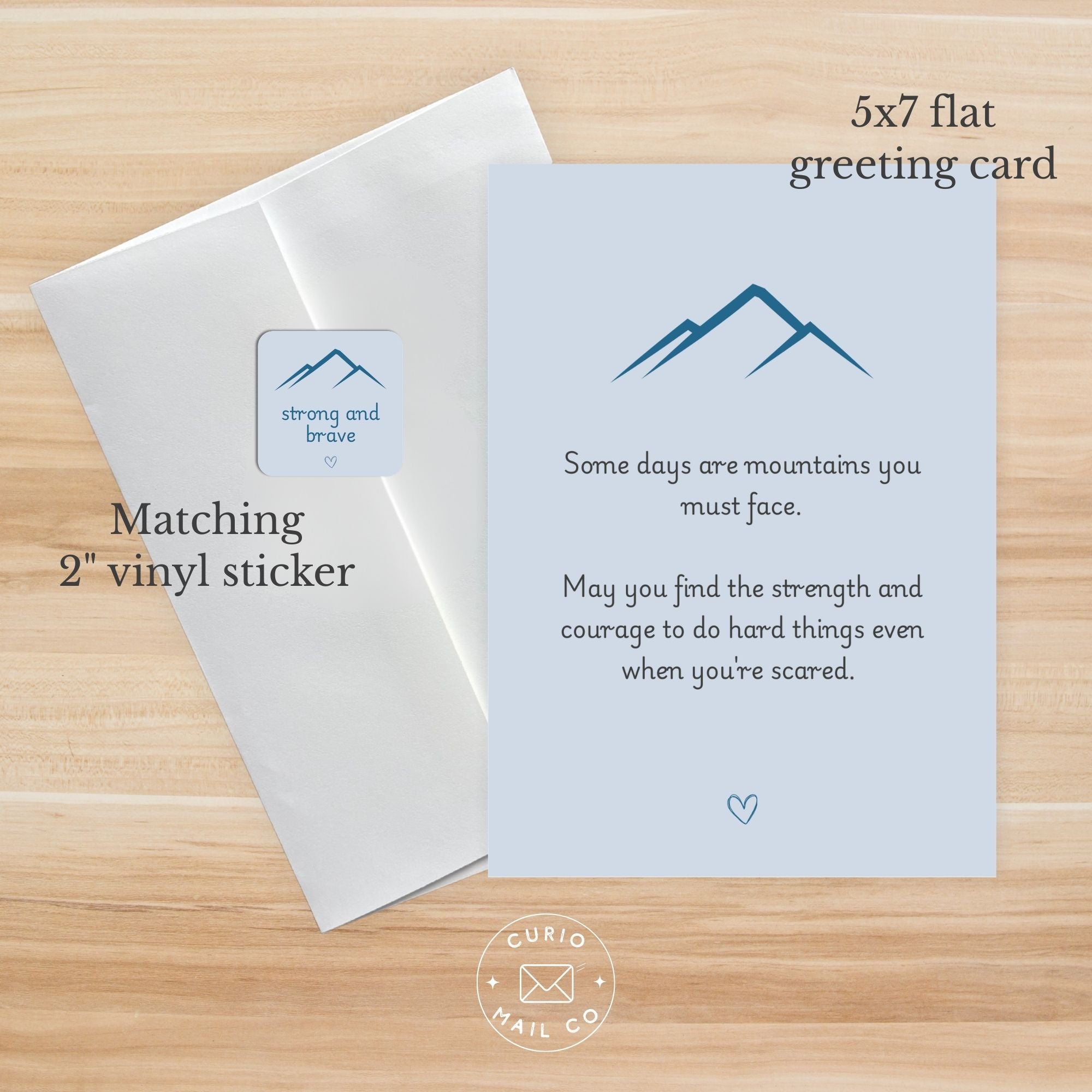 5x7 flat greeting card with mountain design and text on a wooden surface, featuring 'strong and brave' sticker.