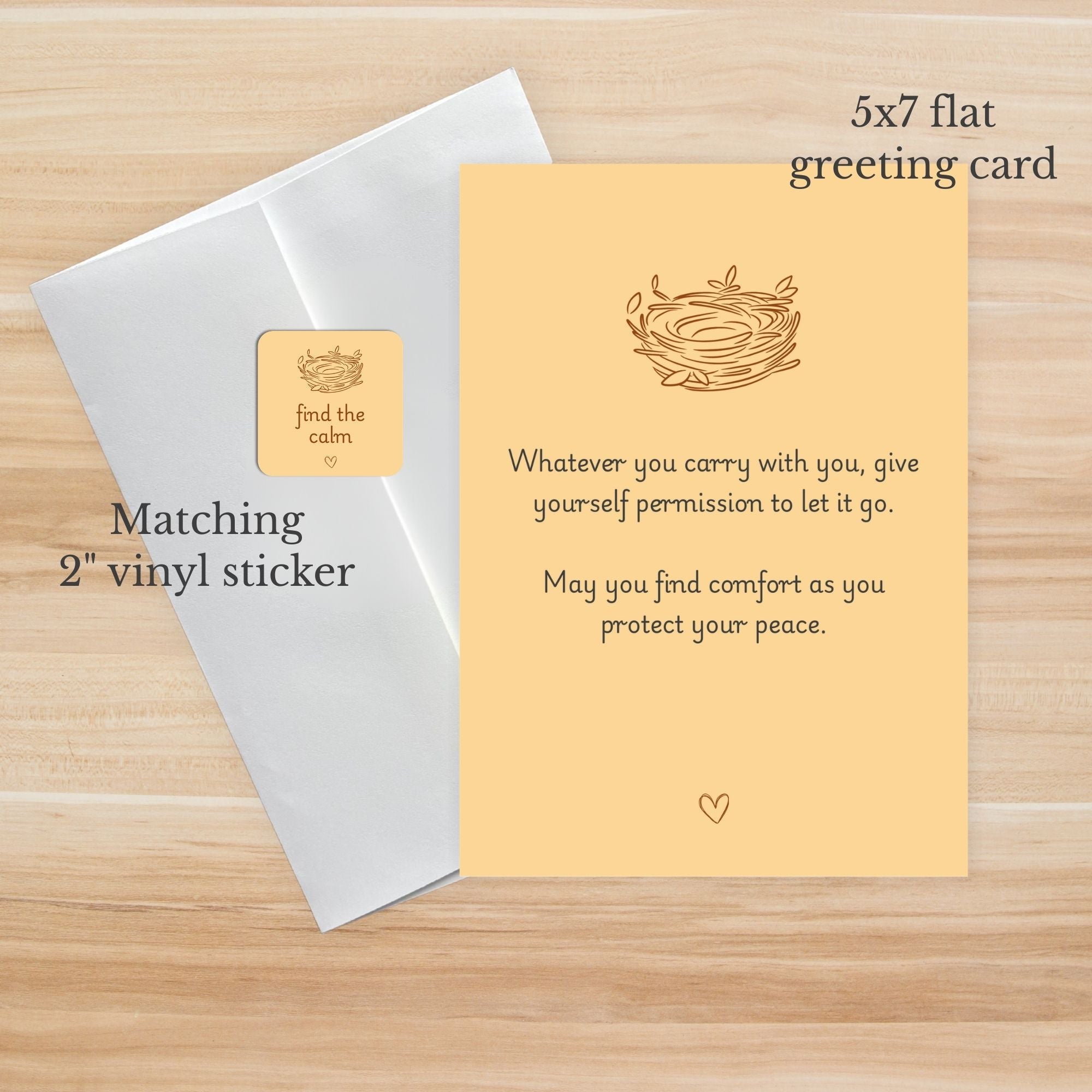 Yellow greeting card with text and a nest illustration, matching white envelope, and gold sticker on a wooden surface.