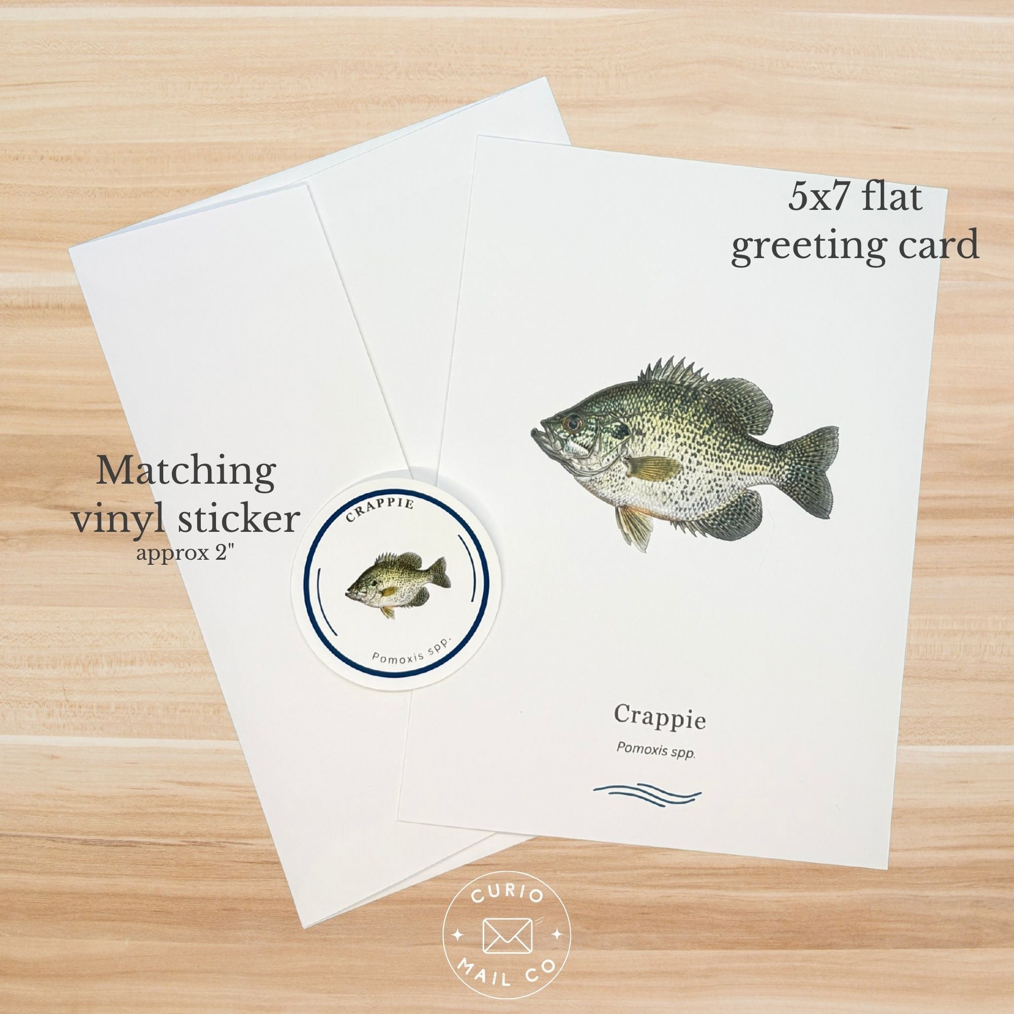 Greeting card with crappie illustration and matching sticker on a wooden surface