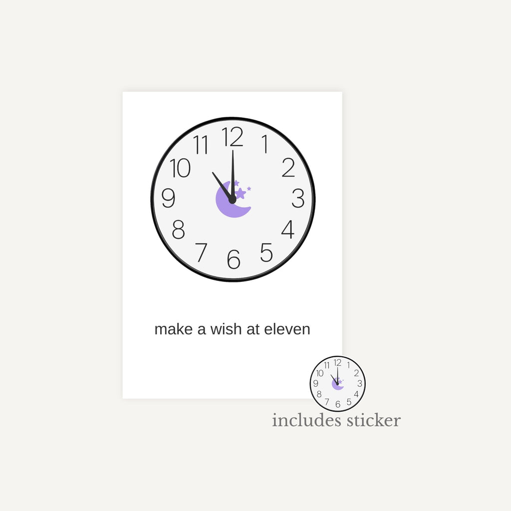 Wall clock with decorative sticker and text 'make a wish at eleven' on a white background
