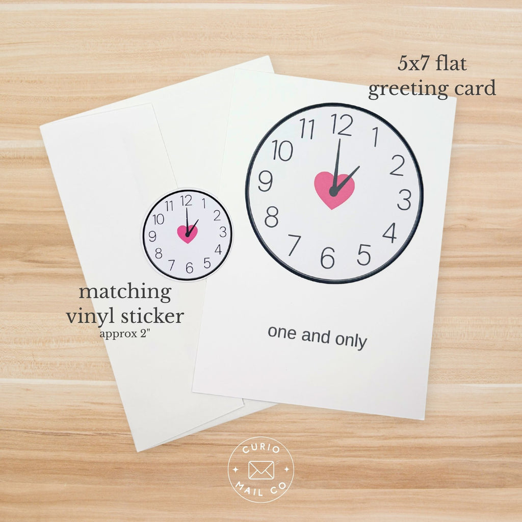5x7 flat greeting card with clock design and matching vinyl sticker on a wooden surface.