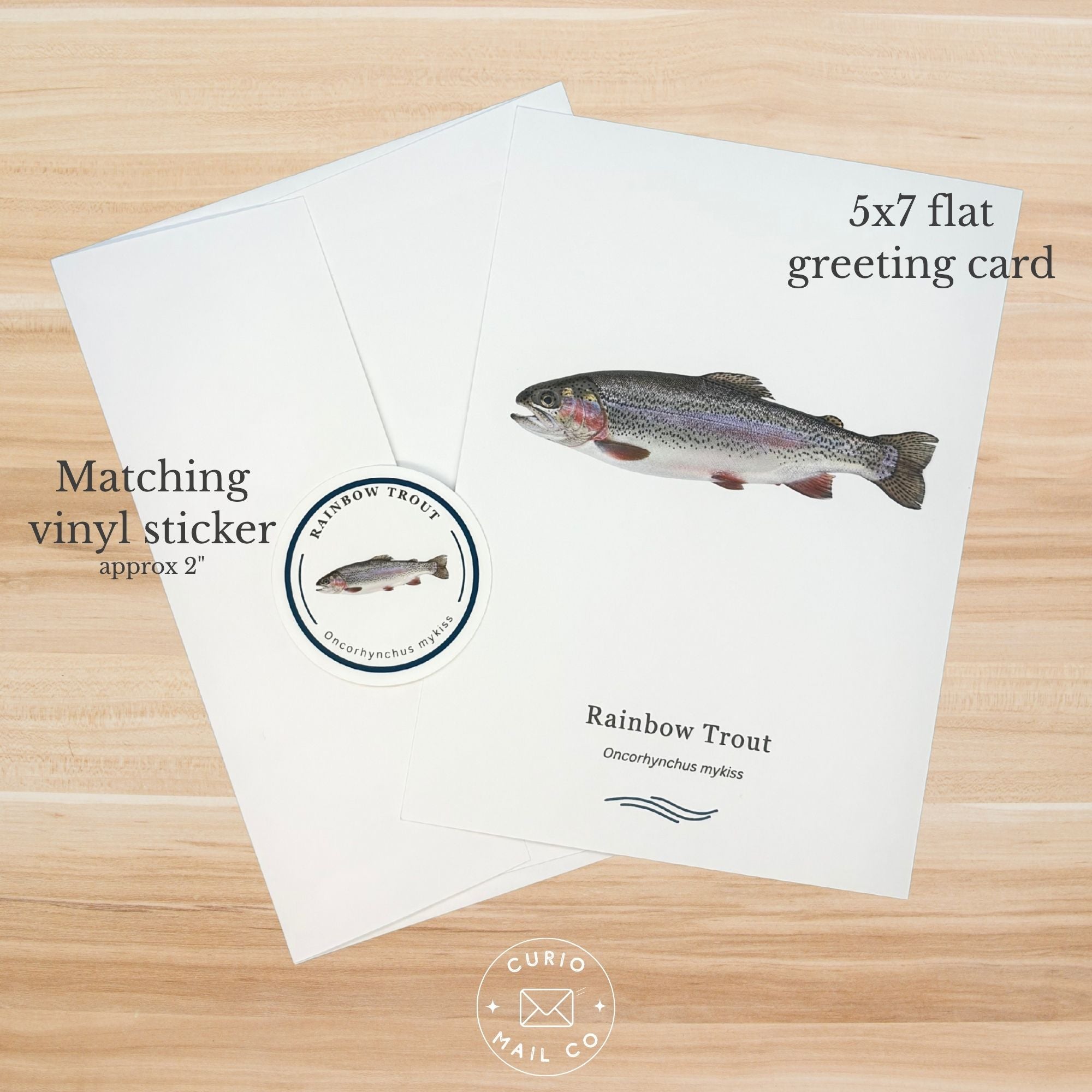 5x7 flat greeting card with rainbow trout illustration and matching vinyl sticker on a wooden surface.