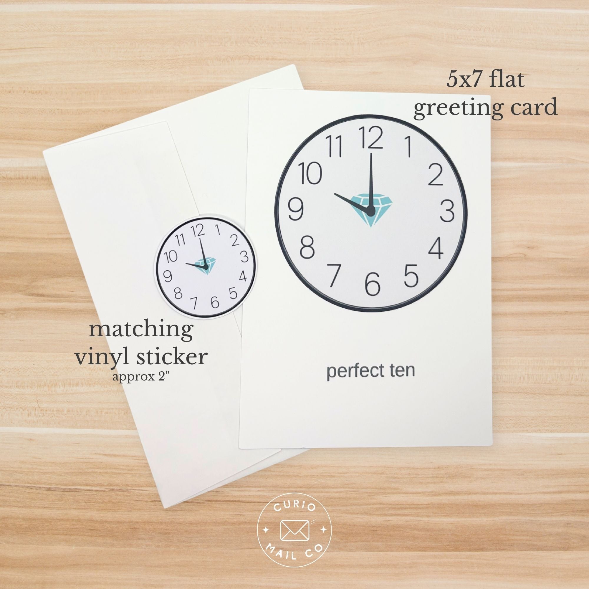 5x7 flat greeting card with clock design and matching vinyl sticker on a wooden surface, featuring 'Curio Mail Co' logo.