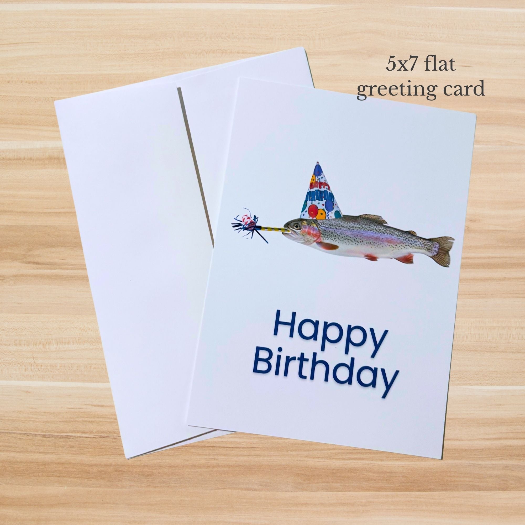 Greeting card with a fish wearing a party hat and the text 'Happy Birthday' on a wooden surface.