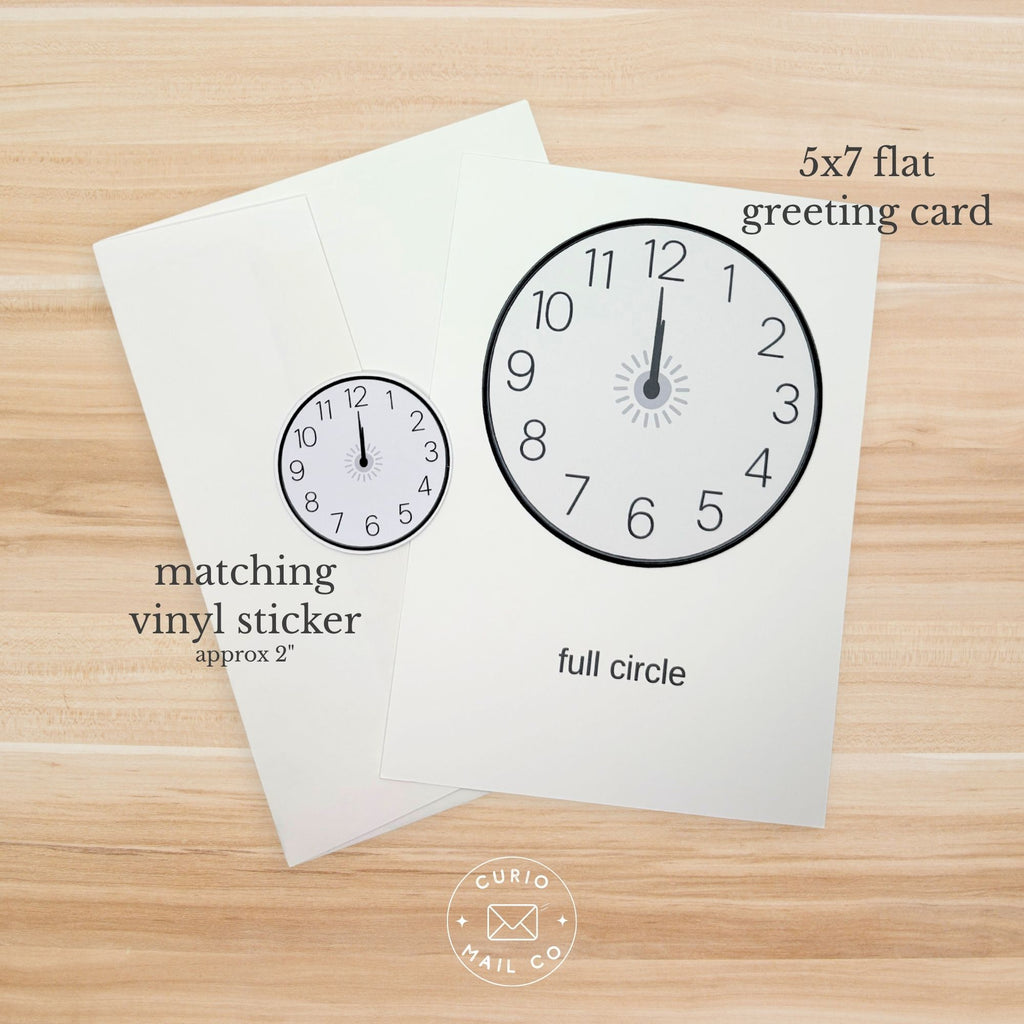 Greeting card with clock design and matching vinyl sticker on a wooden surface, featuring Curio Mail Co branding.