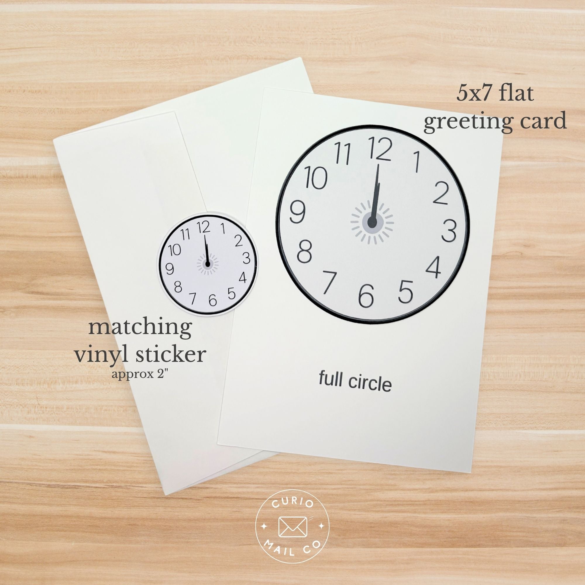 Greeting card with clock design and matching vinyl sticker on a wooden surface, featuring Curio Mail Co branding.