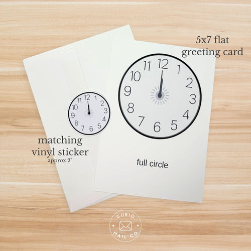 Greeting card with clock design and matching vinyl sticker on a wooden surface, featuring Curio Mail Co branding.