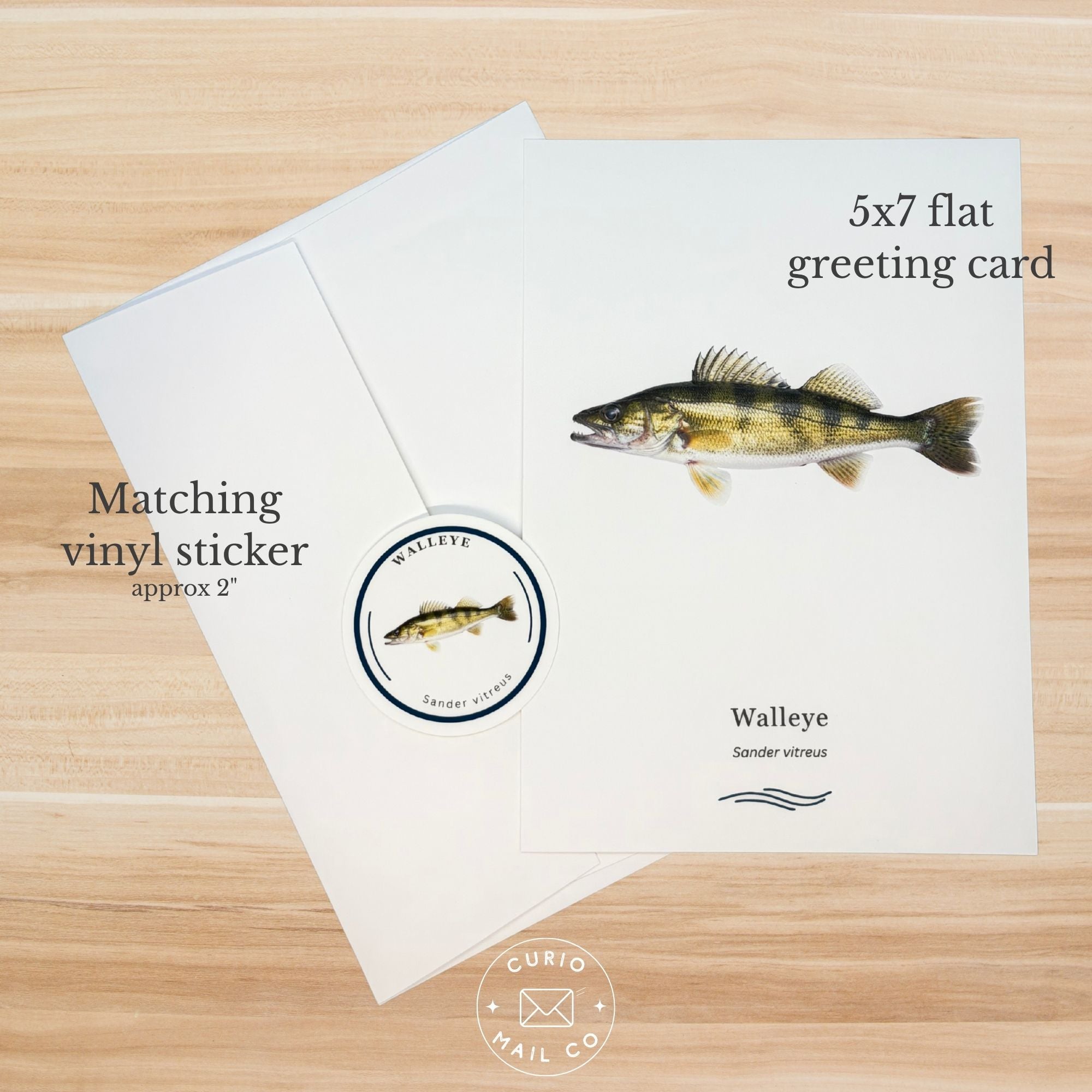 5x7 flat greeting card with walleye illustration and matching vinyl sticker on a wooden surface.