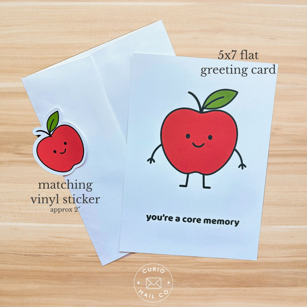 5x7 flat greeting card with a red apple character and matching vinyl sticker on a wooden surface.